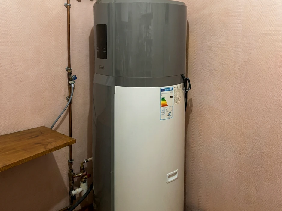 Chauffe-eau thermodynamique installé dans une pièce intérieure, contre un mur rose