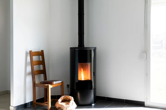 Poêle noir moderne avec flammes brûlantes et sac à pellet dans le salon