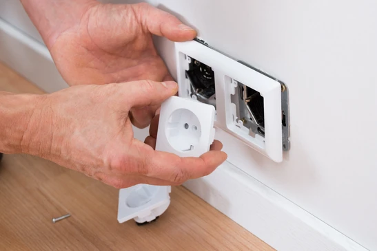 Intérieur résidentiel, mains d'une personne installant une prise électrique murale