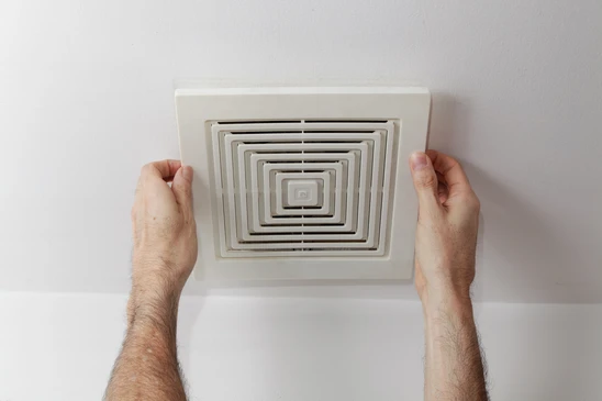 Technicien en gants installant un conduit de ventilation flexible métallisé dans un environnement intérieur
