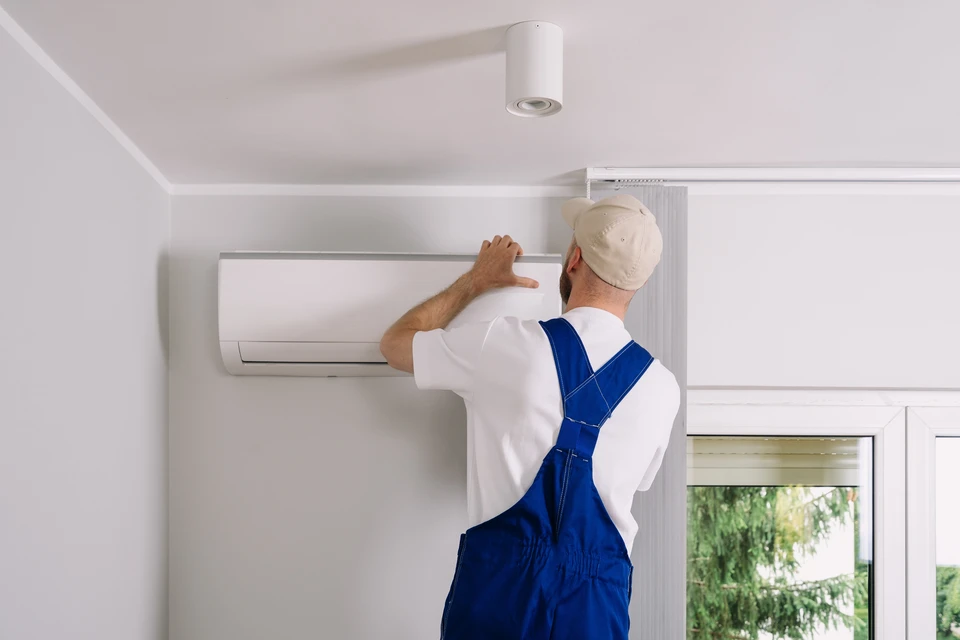 Intérieur résidentiel avec climatiseur mural blanc monté au plafond en fonctionnement, diffusant de l'air frais visible par effet de brume