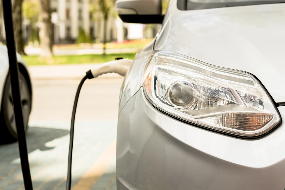 Scène extérieure montrant une voiture électrique blanche en cours de recharge