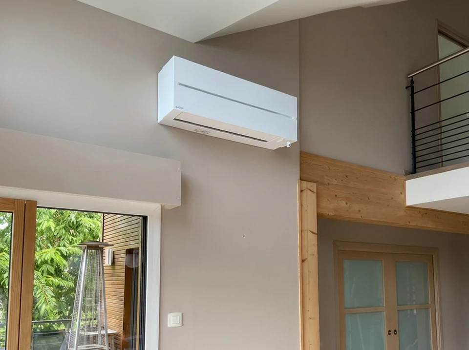 Photographie en couleur naturelles d'un chantier de rénovation intérieure avec plusieurs artisans en tenue professionnelle (vêtements de travail, gilets de sécurité si pertinent) travaillant coordonnément dans un espace résidentiel : un électricien sur une partie du mur, un plombier à proximité, un chauffagiste visible avec ses outils, illustrant la coordination harmonieuse de multiples corps de métier sous une supervision commune. L'ambiance doit être professionnelle et sereine, montrant l'efficacité et l'organisation du travail collectif.
