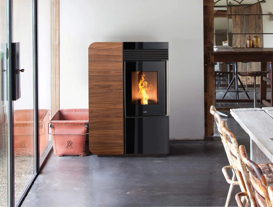Intérieur moderne avec poêle à bois cylindrique noir en fonctionnement, flammes oranges visibles à travers la vitre